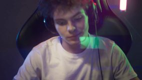 Teenager Using Keyboard To Write Messages To Team In Computer Game. Teenager In Electronic Audio Headset Playing In Video Game Tournament. Teenager Frustrated From Playing Challenging Video Game
