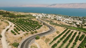 This stock video features an aerial view of a road winding toward the Sea of Galilee in Israel.