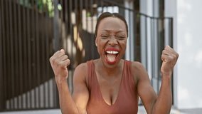 Excited african american woman standing proud on city street, screaming in triumph, cheering her victory and success with raised arms - Powered by Shutterstock - Get 15% off with code: PIKWIZARD15