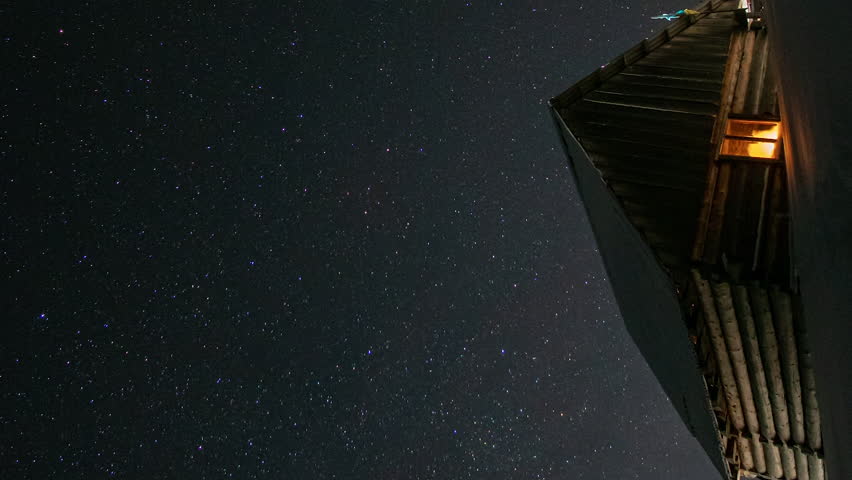 Time lapse of Star trails in the night sky, Wooden house in the mountains in winter, Stars move around a polar star. vertical footage