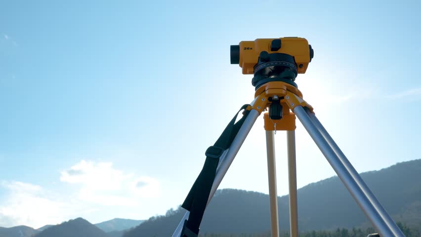 Surveyors equipment (theodolite or total positioning station) on the construction site of the road or building with construction machinery background in the field of mountains slow motion footage Royalty-Free Stock Footage #3392593631