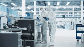 Two Specialists in Sterile Suits Walking In Electronics Factory Research Center. Scientist With Tablet And Engineer Approaching Soldering Jet Printer And Starting Production Process Of Circuit Boards. - Powered by Shutterstock - Get 15% off with code: PIKWIZARD15