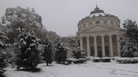 Winter snowfall 4K video in Bucharest. Beautiful wide angle view during a snowfall over Romanian Atheneum landmark building from Romania. Travel to Bucharest.