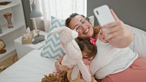 Mother and daughter sharing a relaxed morning video call, comfortably sitting on the bed, smiling and talking together in a cozy bedroom