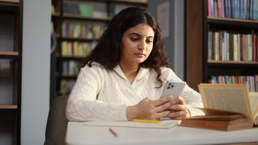 Attractive young curly woman student get notification and feeling upset reading bad negative news message exam result sitting at desk at university library Disappointment concept Royalty-Free Stock Footage #3392755589
