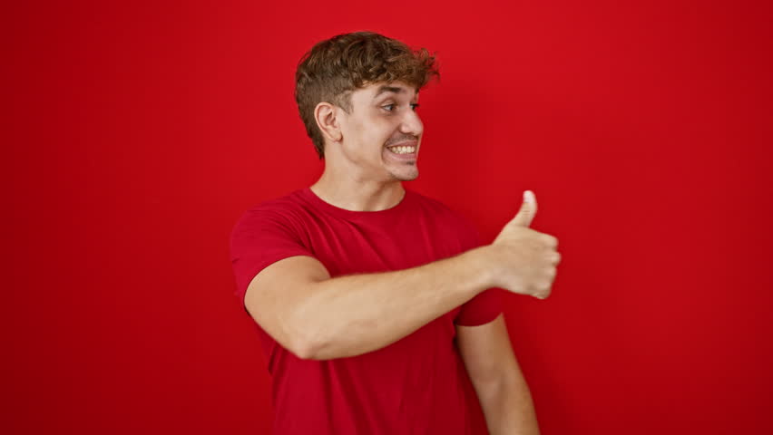 Young, handsome hispanic man smiling with confidence over isolated red background, giving a thumbs up gesture in joyful celebration