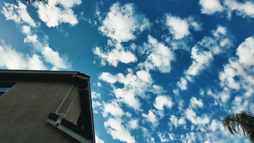 Looking up at side of house motion lapse with clouds moving through the sky 