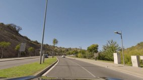 First person view, FPV, from dashcam of car driving along the Algarve Coast in Portugal in Albufeira, driving in the city. Road trip video in POV, with blue sky