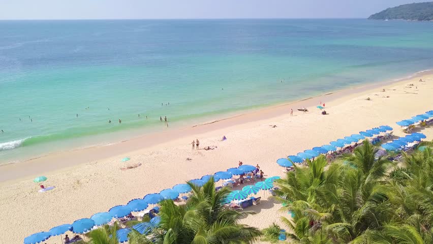 High-season there are umbrellas and coconut trees is located beachside at Hat Karon Phuket Thailand country.