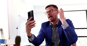 Angry businessman manager swearing at mobile phone screen over video call 4k movie. Problems of remote work professional burnout in business concept