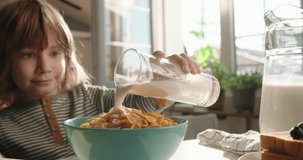 Happy calm boy enjoying bowl of cereal with milk for breakfast in bright and modern kitchen. Promotional clip, slow motion cinematic. Nutritional value of meal, ideal choice for children's morning