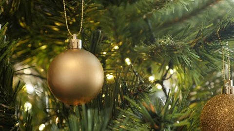 Bauble with fairy-lights on the artificial tree branch close-up 4K 2160p 30fps UltraHD footage - Golden color Christmas ornament 3840X2160 UHD video