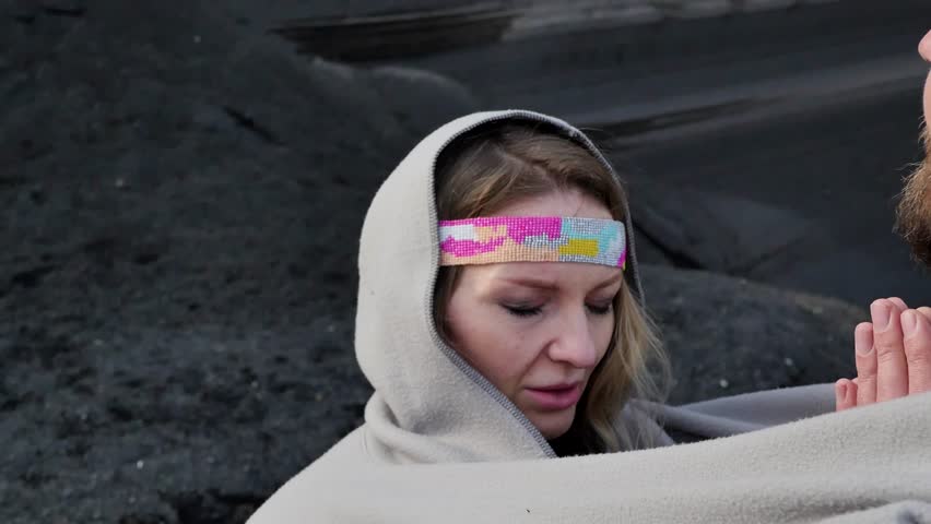 Close-up of a man and a woman meditating while standing, wrapped in a blanket, and doing namaste, closing their eyes. Meditation practice outdoors in the mountains. Finding harmony with yourself
