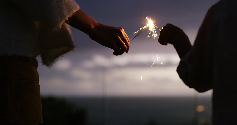 People, hands and sparklers at night for new year celebration, event or outdoor fun together. Children walking and playing with light or burning fireworks late for glow or sparks outside in the dark