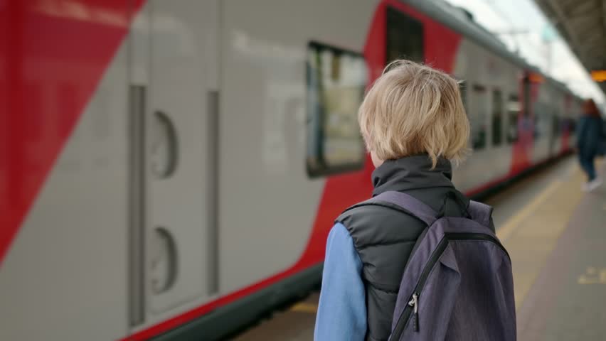 A cute teenage boy is waiting for a train on a railway platform or subway station. Metropolis transport system. Public transport in a big city Royalty-Free Stock Footage #3392968675