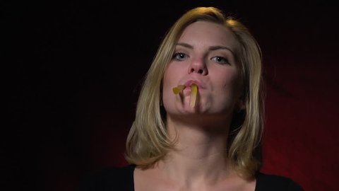 The merry blonde grimaces, makes herself a mustache from jelly worms and then shoves herself into her mouth