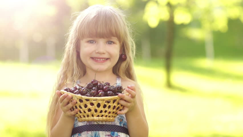 Child holding a basket of cherries in the hands
