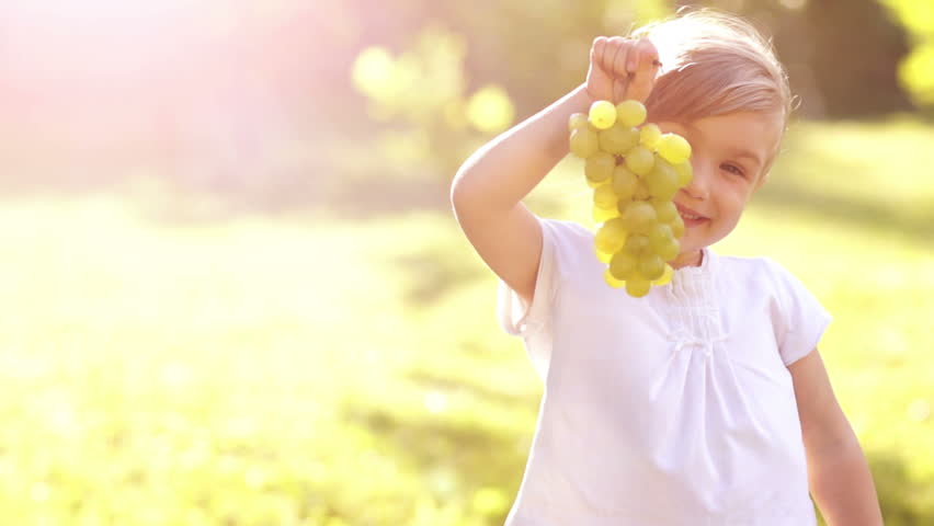 Portrait of happy girl with grapes. Thumbs up. Sign Ok.
