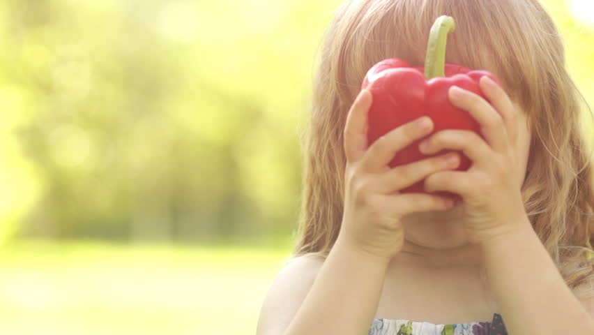 Portrait of a girl playing with a vegetable pepper in Sunny day. Slow motion
