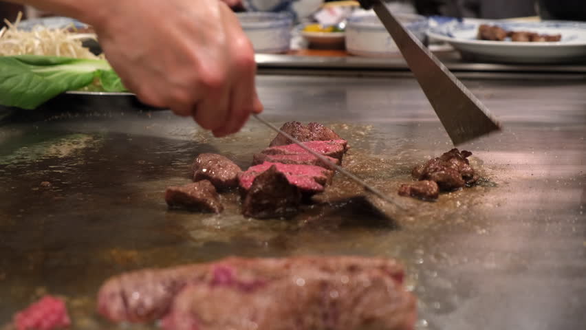 Chef grilling Kobe beef on iron plate in front of guests, Kobe, Japan.