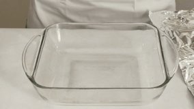 Aluminum foil on a baking pan. Chef gently press the foil into the inside of the glass pan for cooking chicken meat, close up step by step video