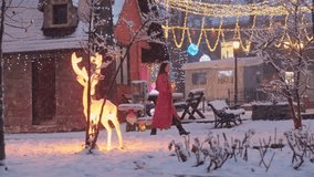 Beautiful tourist woman in festive mood walking near Santa Claus village with Christmas lights and reindeer decorations. Fairytale wonderland winter season - Powered by Shutterstock - Get 15% off with code: PIKWIZARD15