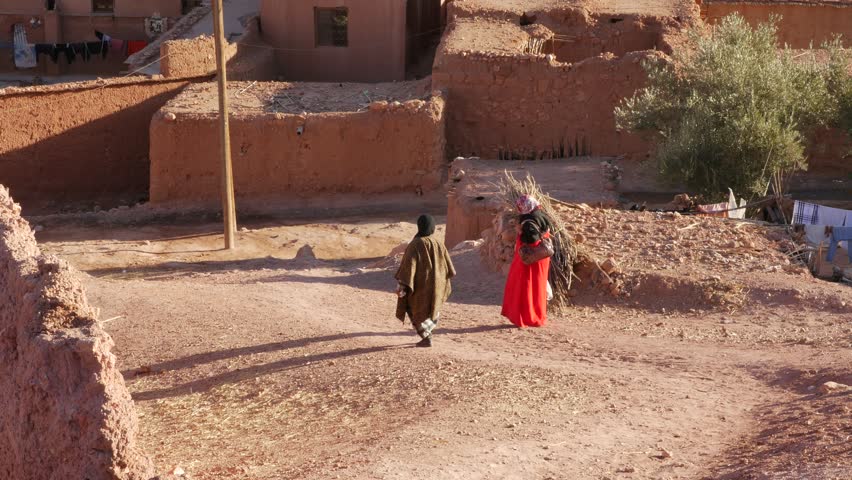Woman with colourful clothes walking in village in valley in the foothills of the Atlas mountains in Morocco – 4K