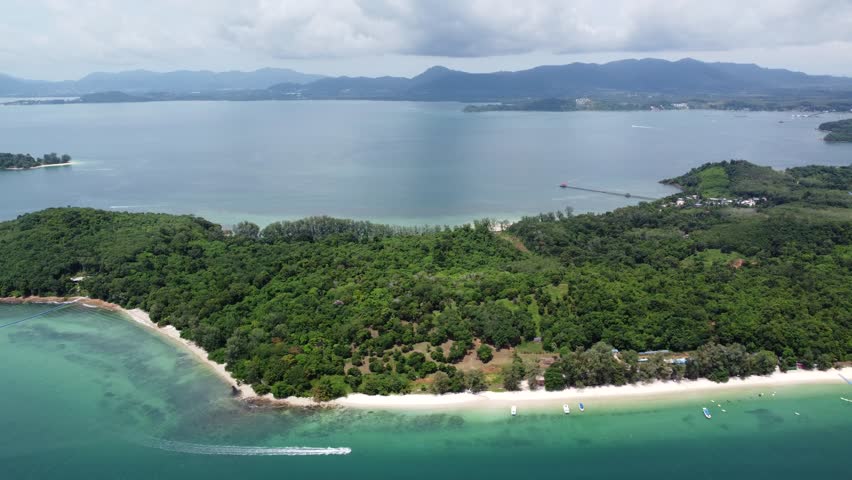 Aerial drone view of speedboat sailing near Ko Naka Yai a tropical island near the coast of Thailand Phuket showing the white beaches and trees and the mountains in the far background on mainland 4k Royalty-Free Stock Footage #3393249705