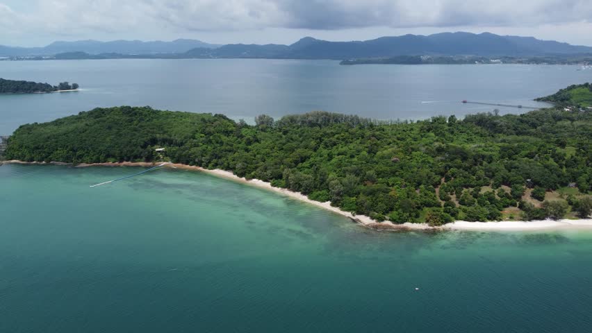 Aerial bird view of Ko Naka Yai a tropical island near the coast of Thailand Phuket showing the white beaches and trees and the mountains in the far background on mainland 4k high resolution quality Royalty-Free Stock Footage #3393264237