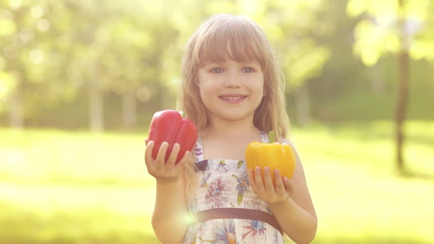 Portrait of a child hugging two vegetable pepper. Slow motion
