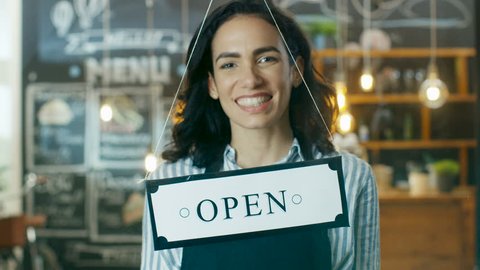 Beautiful Young Cafe Owner Flipping Storefront Sign From Close to Open and Welcoming New Customers into Her Modern Looking Stylish Coffee Shop. Slow Motion. Shot on RED EPIC-W 8K Helium Cinema Camera.