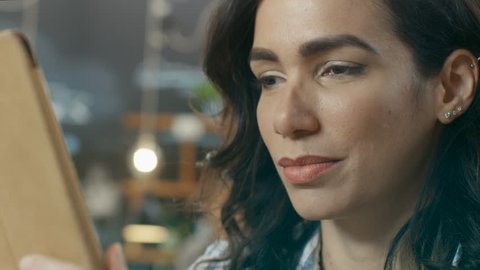Portrait of the Beautiful Hispanic Woman Uses Tablet Computer while Sitting in the Stylish Cafe. She Makes Swiping Gestures. Shot on RED EPIC-W 8K Helium Cinema Camera.
