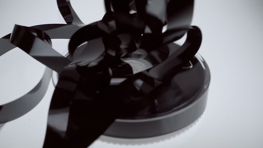 On the coil VHS the magnetic tape falls on it in large quantities on blue background. Closeup. Slow mo, slo mo, slow motion, high speed camera, 240fps, 250fps