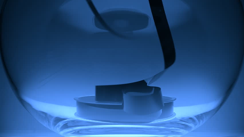 In the glass bowl lies a coil VHS and the magnetic tape pull up on blue background. Closeup. Slow mo, slo mo, slow motion, high speed camera, 240fps, 250fps