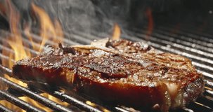 Appetizing juicy piece of steak fried until golden brown. Tongues of flame on black background. Juicy meat sprinkled salt on grill. Smoky aroma and delicious charcoal make every dish unforgettable