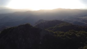 Top of a hill against the backdrop of an incredible landscape of mountains and hills at sunset. Travel destination. The lights of a sun. Incredible smooth cinematography video. Travel film. Bright sun
