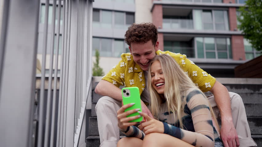 Portrait of generation z couple sitting outdoors in the city and taking selfie.