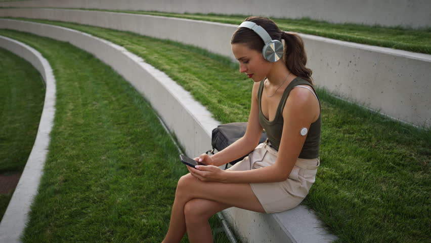 Diabetic woman sitting outdoors, watching social media content on smart phone.