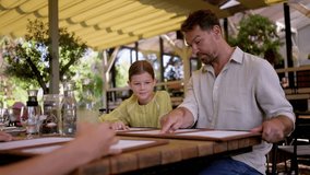 Father and daughter reading menus in a restaurant, choosing food and drinks. - Powered by Shutterstock - Get 15% off with code: PIKWIZARD15