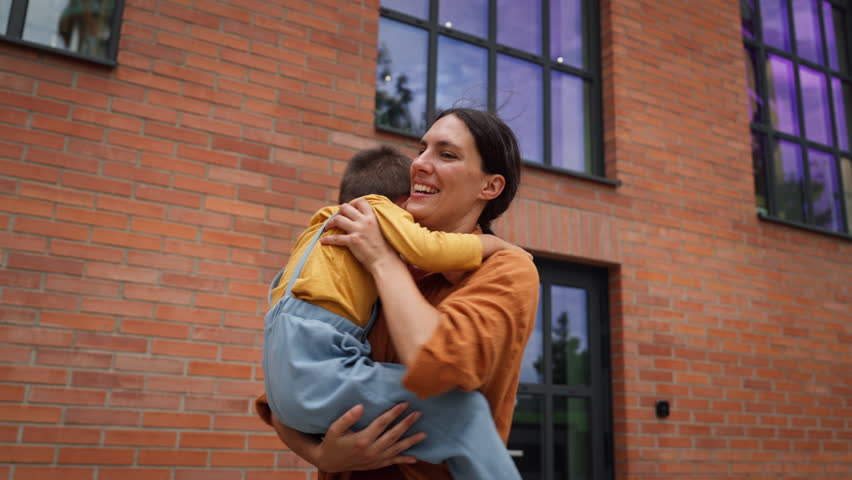 Hard-working, ambitious mother picking up son from school, greeting him in front of the school building. Concept of work-life balance for women. Royalty-Free Stock Footage #3393577487