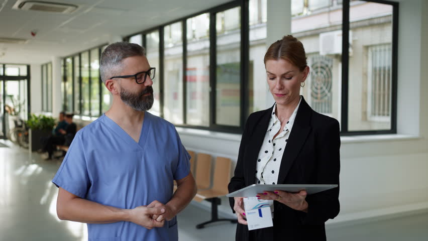 Pharmaceutical sales representative talking with doctor in medical building. Ambitious hospital director consulting with healtcare staff. Woman business leader. Royalty-Free Stock Footage #3393582989