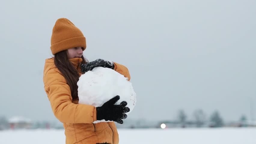 Happy girl playing outdoors with a snow in winter cold weather, winter holidays