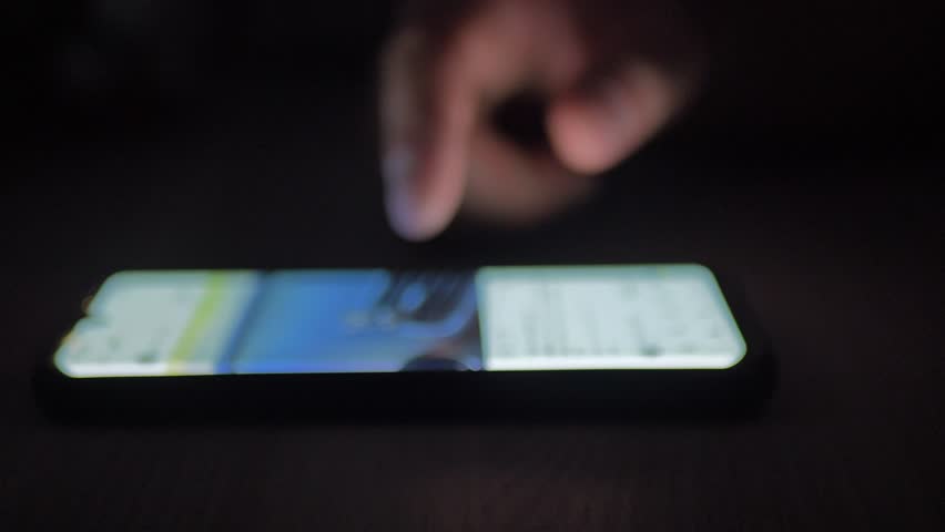 Using a mobile phone in a dark room. Human hands scroll through photos of cars. Trendy social media