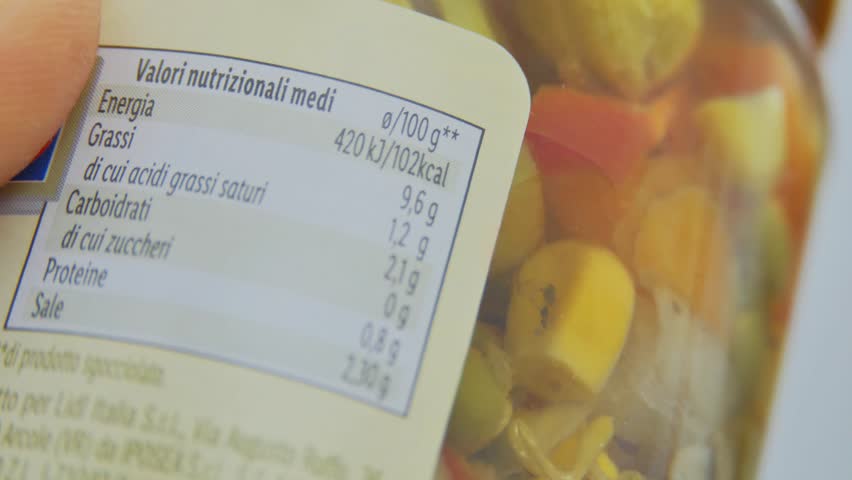 Finger moving slowly across nutrition label, examining calorie information on a packet of food, extreme closeup macro view