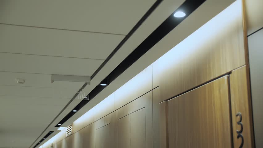 Modern hidden ceiling lamps in minimalist hall interior, hidden LED backlight. Minimalist Interior with lighting equipment. Contemporary modern lamp. Luxury Chandelier, slow motion dolly shot. Royalty-Free Stock Footage #3393823625