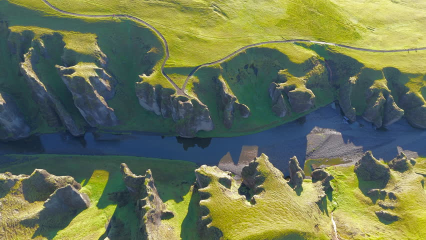 Aerial view of powerful cliffs with sparse vegetation and frightening heights with deep gorge and river flowing in it. Icelandic phenomenal landscapes. High quality 4k footage Royalty-Free Stock Footage #3393881203