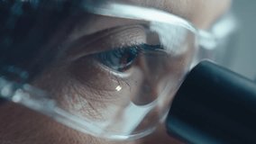 Eyes of female scientist in protective glasses looking through microscope during laboratory research. Extreme close-up shot - Powered by Shutterstock - Get 15% off with code: PIKWIZARD15