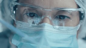 Female chemist in protective face mask, glasses and medical hat dripping liquid substance into test tubes, developing vaccine or conducting research in laboratory. Rack focus, close-up view - Powered by Shutterstock - Get 15% off with code: PIKWIZARD15