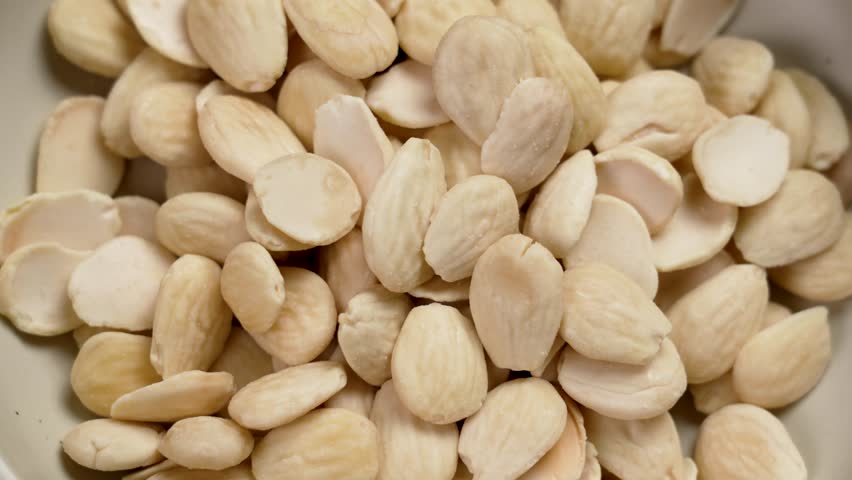 Blanched peeled almonds in a ceramic dish. Shelled raw nuts. Ready-to-eat healthy food close up. Rotation