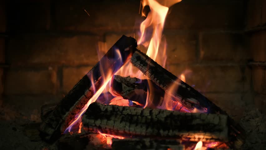 A fireplace with burning logs. Fire in the fireplace. A cozy place to rest. Fire and firewood as background. Burning wood in the furnace. Fire video